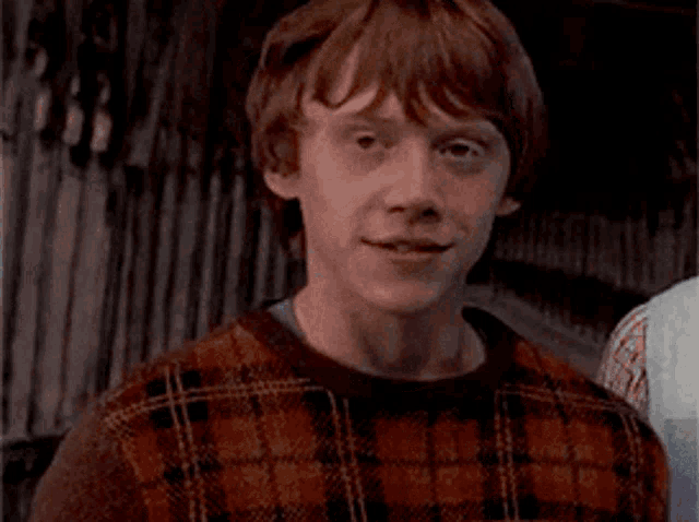 a close up of a man wearing a plaid sweater
