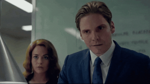 a man in a suit stands next to a woman
