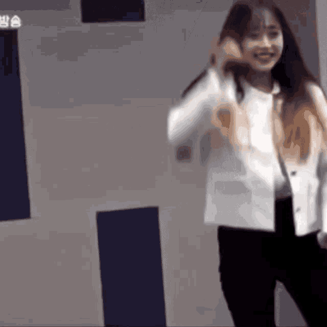 a woman in a white jacket and black pants is smiling and dancing