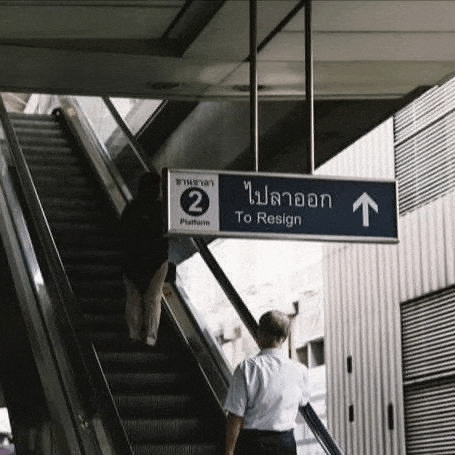 a man is walking up an escalator next to a blue sign that says to resign .