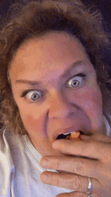 a woman making a funny face while eating a piece of food