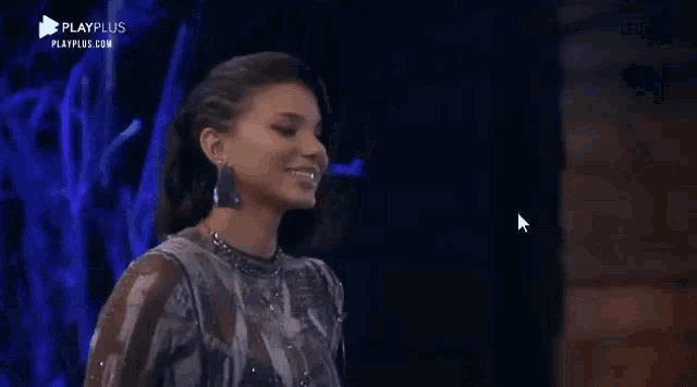 a woman is smiling while standing on a stage in front of a blue light .