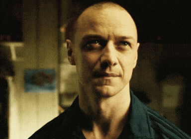 a man with a shaved head wearing a blue shirt looks at the camera