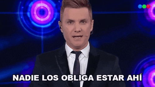 a man in a suit and tie is standing in front of a target and says nadie los obliga estar ahi