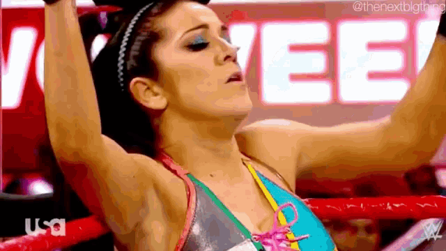 a woman is standing in a boxing ring with her arms up .