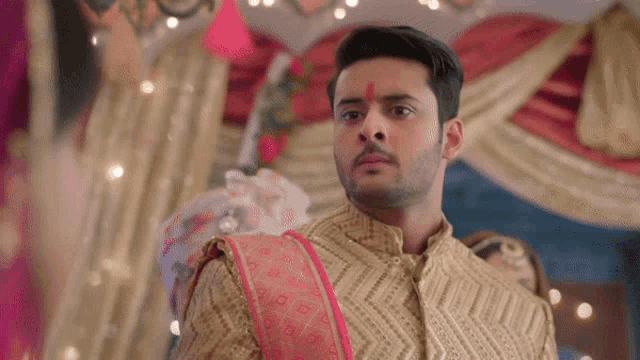 a man with a red bindi on his forehead is standing in front of a woman in a wedding dress .