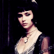 a woman wearing a pearl necklace and a black dress