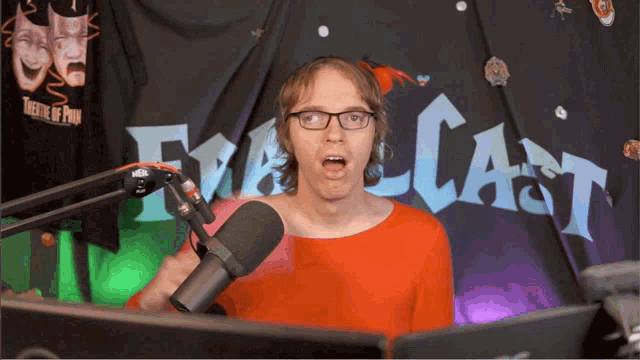 a man wearing glasses stands in front of a microphone in front of a banner that says theatre of providence