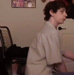 a man in a white shirt is standing in front of a chair