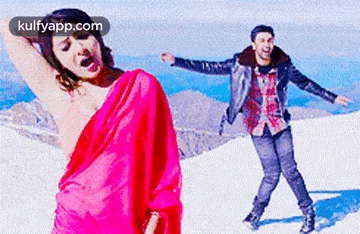 a man and a woman are dancing in the snow . the woman is wearing a pink saree .