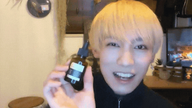 a man with blonde hair is holding a bottle with a dropper