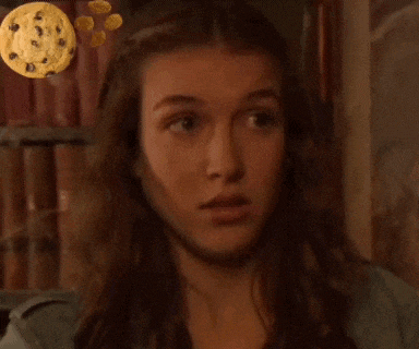 a close up of a woman 's face with a cookie floating in the background