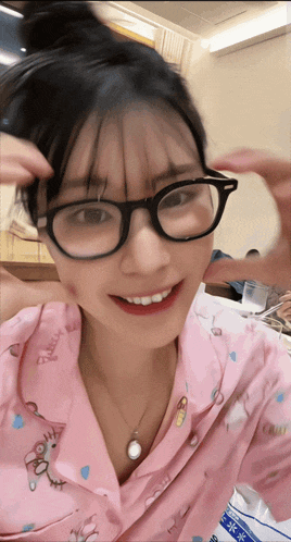 a woman wearing glasses and a pink pajama top that says ' pretty ' on it