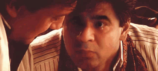two men are looking at each other and one of them is wearing a scarf around his neck .