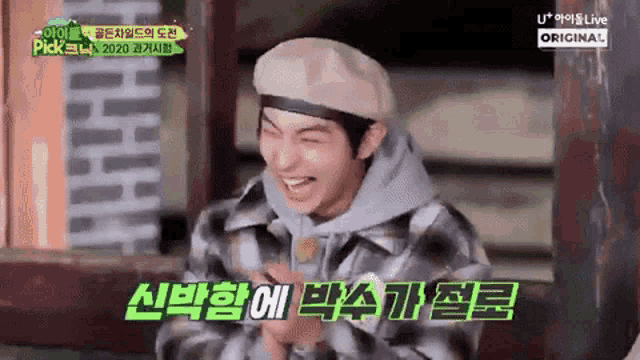 a young man wearing a beret and a plaid jacket is laughing .