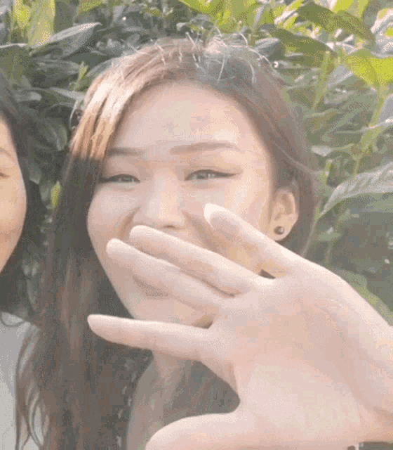 a woman covering her mouth with her hand while another woman looks on .