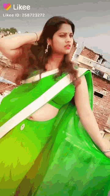 a woman in a green saree is standing in front of a building