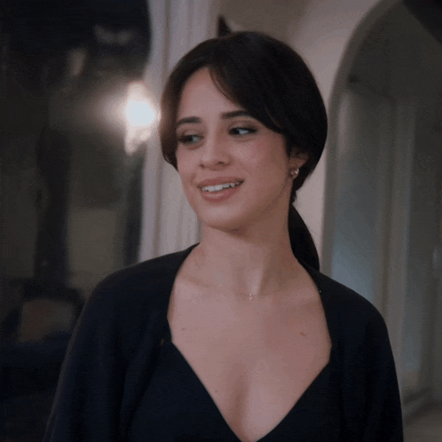 a woman in a black dress with a very plunging neckline smiles