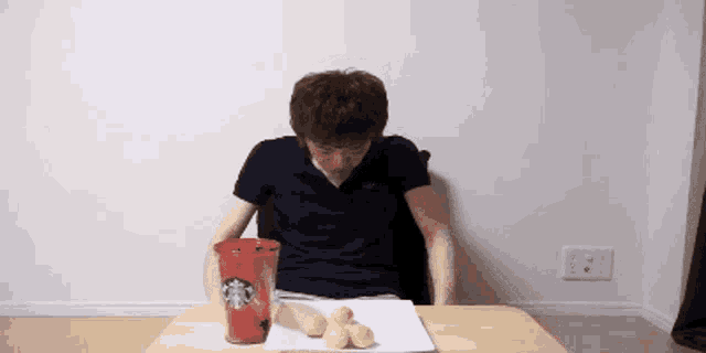 a man is sitting at a table with a starbucks cup
