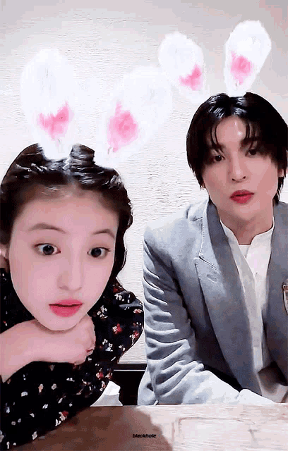 a girl wearing bunny ears sits next to a man wearing a suit