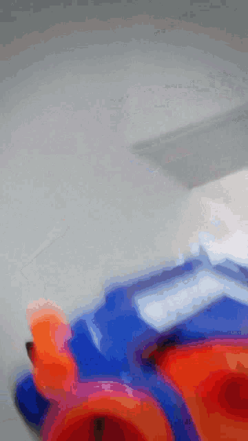 a blurred image of a blue and orange toy with a gray background