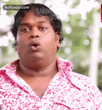 a man is wearing a pink and white shirt and making a funny face .