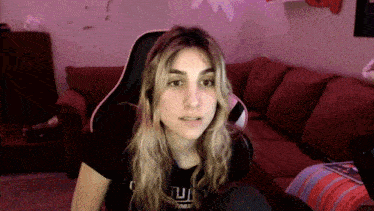 a woman sitting in front of a red couch wearing a t-shirt that says " tu "