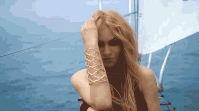 a woman wearing a bracelet on her wrist is sitting on a boat in the ocean