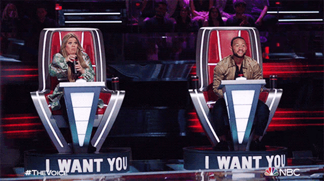 a man and a woman are sitting in chairs that say " i want you "