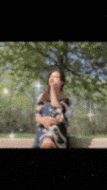 a blurry picture of a woman sitting under a tree with her eyes closed