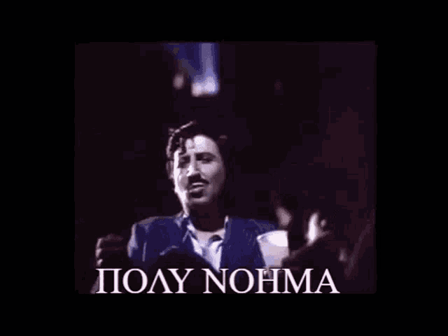 a man in a suit and tie is singing into a microphone in a dark room .