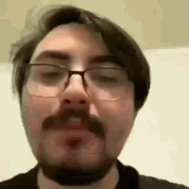 a close up of a man with glasses and a beard .