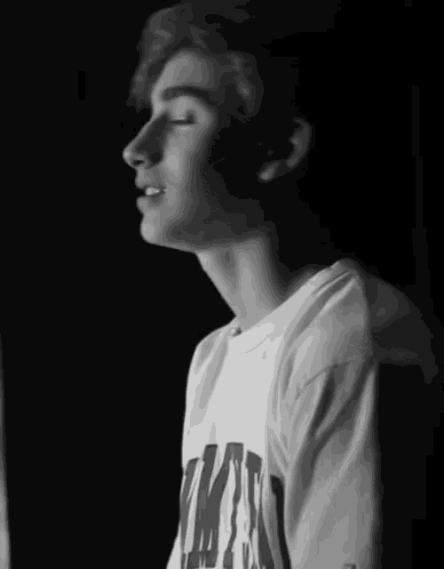 a black and white photo of a young man wearing a white t-shirt that says ymca on it
