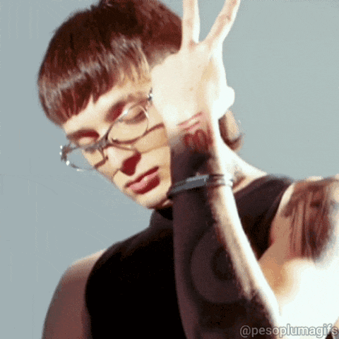 a man with glasses and a tattoo on his arm is giving the peace sign