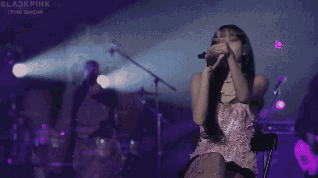 a woman in a pink dress singing into a microphone on a stage