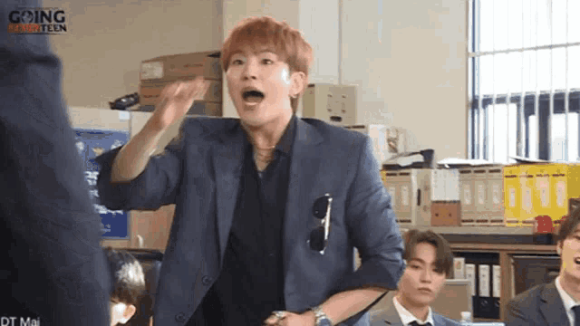 a man in a suit is making a funny face in front of a group of young men in suits .