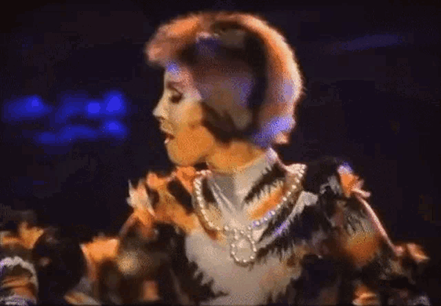 a woman is wearing a tiger costume and a pearl necklace on a stage .