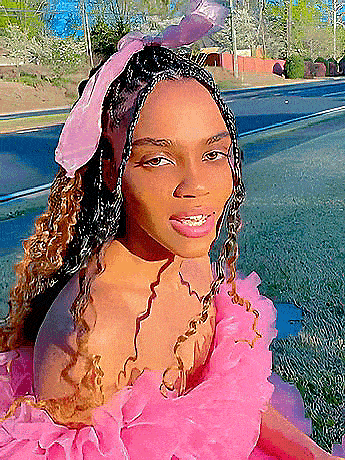 a woman wearing a pink dress and a pink bow in her hair is sitting on the side of the road .