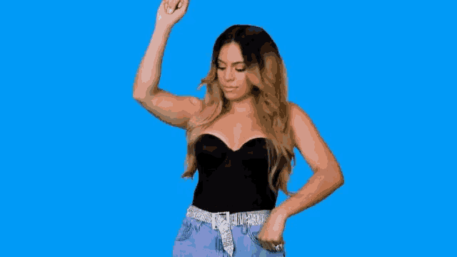 a woman in a black top and purple jeans is dancing with her hands in the air .