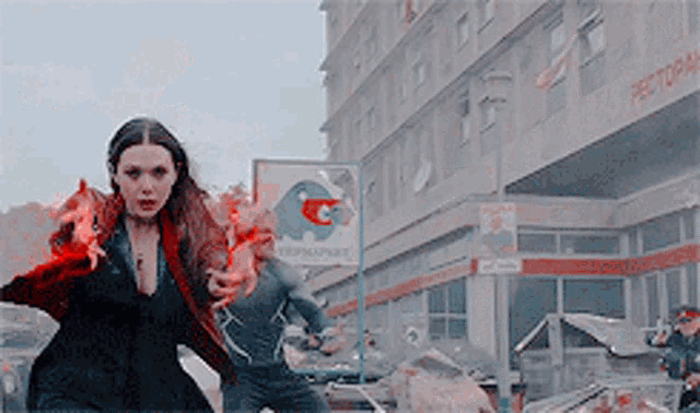 a woman with red hair is running down a street in front of a building with a restaurant sign .