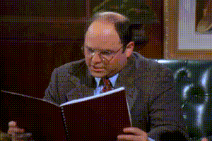a man in a suit and tie is sitting in a chair reading a book .