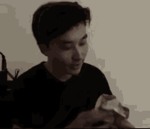 a man in a black shirt is eating a sandwich .