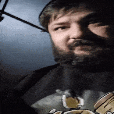 a man with a beard is wearing a black shirt with a picture of a cat on it