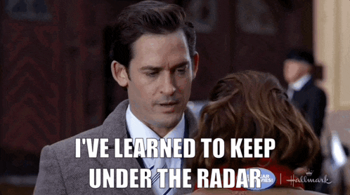 a man in a suit and tie is talking to a woman and says i 've learned to keep under the radar