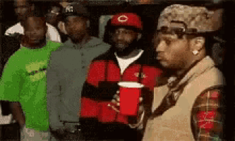 a man is holding a red cup in front of a group of people .