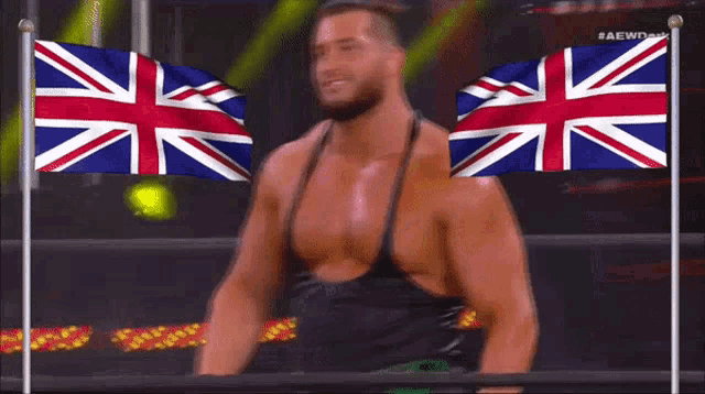 a wrestler is smiling in front of two british flags .