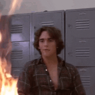 a man in a plaid shirt is standing in front of a wall of lockers with flames coming out of them .