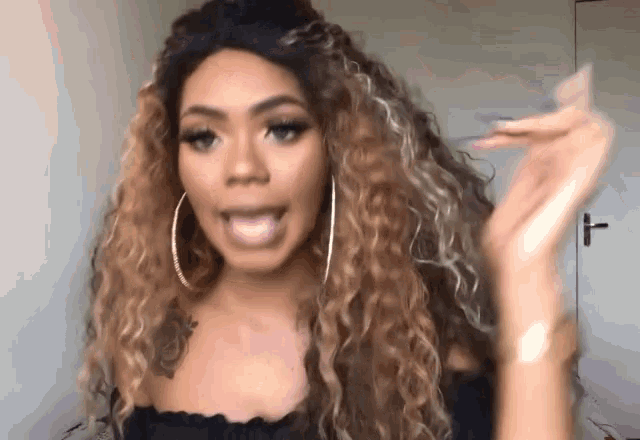 a woman with long curly hair and hoop earrings is talking