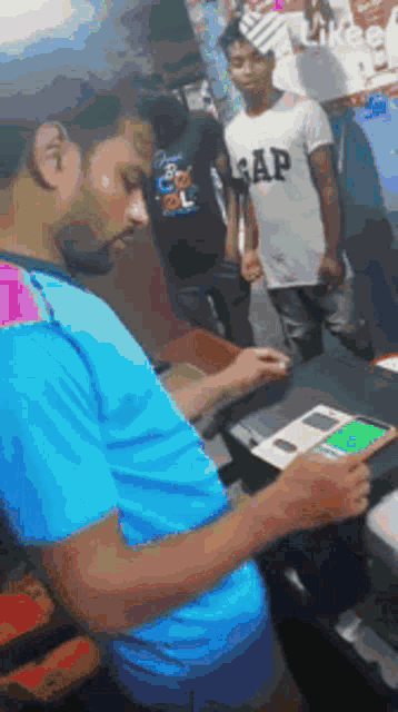 a man wearing a gap shirt is using a cell phone