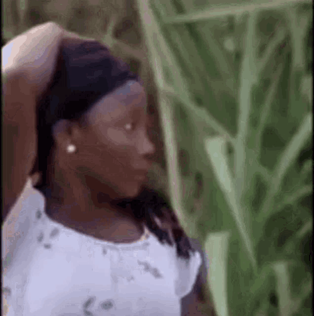 a woman in a white shirt is standing in a field of tall grass and looking at something .